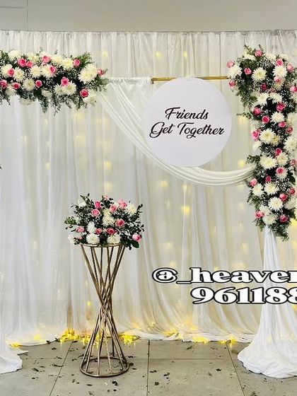 Even simple get-togethers deserve beautiful decor. This clean and elegant backdrop was designed for a friends' gathering, featuring a white drape, fairy lights, and a delicate floral frame.