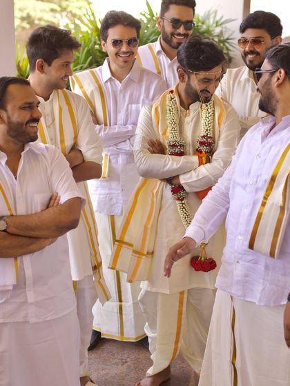 The groom sharing a laugh with his groomsmen, all dressed in traditional South Indian attire. We capture the fun and bond of the groom's party.