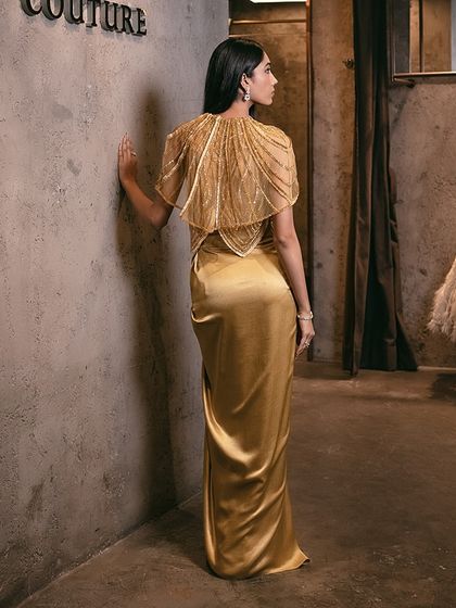The mustard yellow draped set paired with an embellished cape is a striking ensemble, perfect for festive celebrations.