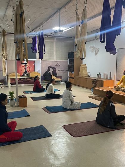A wider view of our meditation hall during a workshop. The space is designed to be a sanctuary, with elements like aerial yoga silks and the prominent Om symbol creating a tranquil environment.