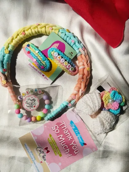 A closer look at one of our personalized gift sets. This one features a pastel rainbow braided headband and custom accessories with the name 'Zainab'.