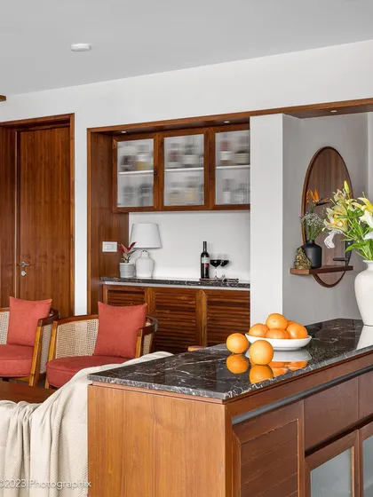 In our 'Gulmohar' project, this niche was transformed into a versatile bar and crockery space. The unit combines veneer, fluted glass, louvered shutters, and a marble buffet top for a vintage feel.