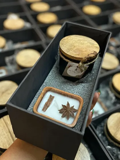 This image shows the contents of our corporate hamper, featuring a black jar candle and a spice-topped candle. The combination of modern and rustic elements makes for a versatile and appealing gift.