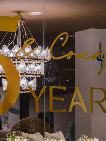 The anniversary branding applied to a glass surface, with a chandelier reflected in the background. This image captures our philosophy of integrating decor at every level for a cohesive experience.
