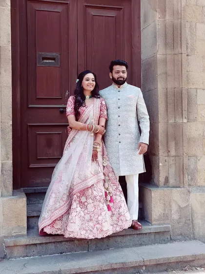 A perfect pair. The bride's soft pink look beautifully complements the groom's elegant attire, creating a timeless wedding portrait.