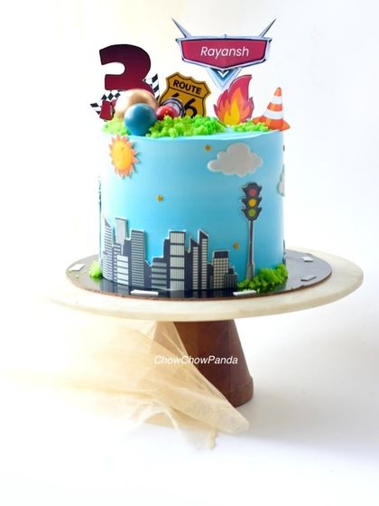 A transport-themed cake for a 3rd birthday. This Choco Vanilla cake features a city skyline, road signs, and a traffic light for a busy city feel.