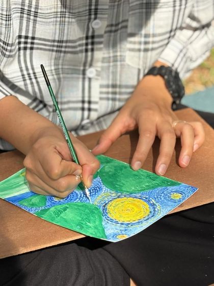 Painting can be a meditative experience. Here, a participant is carefully adding details to their version of 'Starry Night' in a mindful art session.