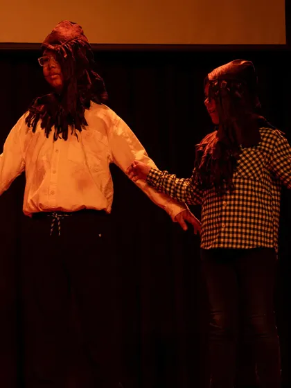 Two actors in character, demonstrating how students learn to create relationships and interact physically on stage.