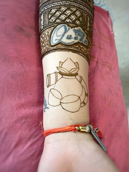 Incorporating an existing tattoo into the mehndi design. Here, the "Queen" tattoo is framed and highlighted by the henna patterns.