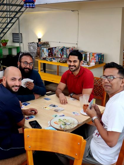 Four friends are all smiles during a card game. My cafe is a place where you can unwind, have fun, and make lasting memories.