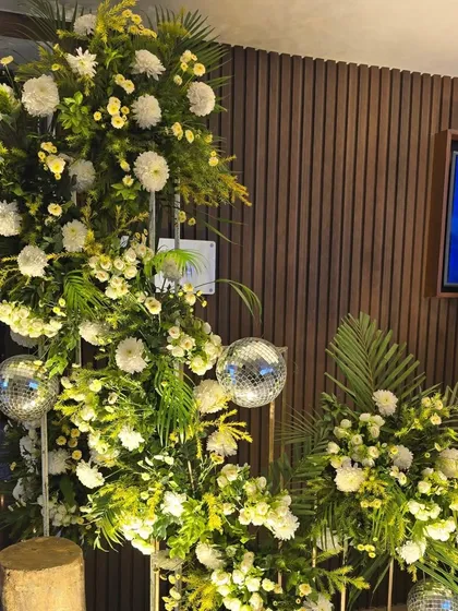 A creative floral arrangement in the shape of a crescent moon, accented with small disco balls for a touch of sparkle.
