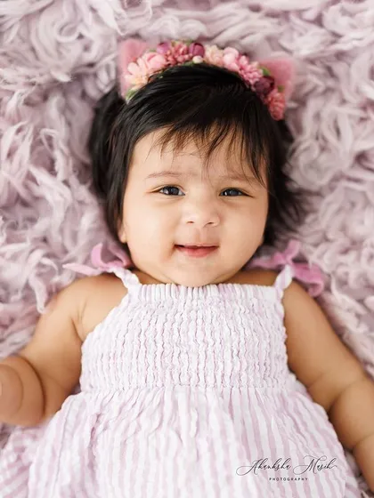 A bright, happy smile from this little one. The combination of the soft purple texture and her joyful expression makes for a heartwarming portrait.