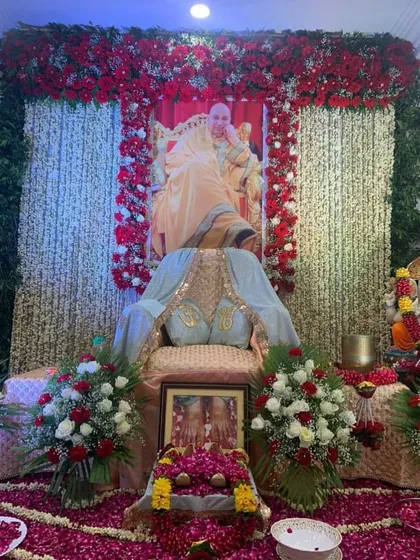 This is a classic Guruji Satsang backdrop I designed, featuring long, hanging strings of fresh white tuberose (rajnigandha). The stage is completed with red rose arrangements and a thick carpet of rose petals on the floor.