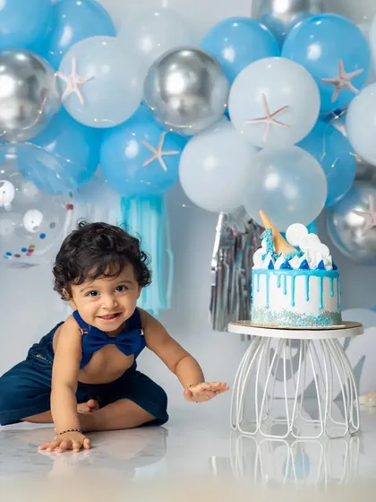 Ready for his ocean-themed cake smash. This little boy looks dapper in his blue bow tie, surrounded by a sea of blue and silver balloons.