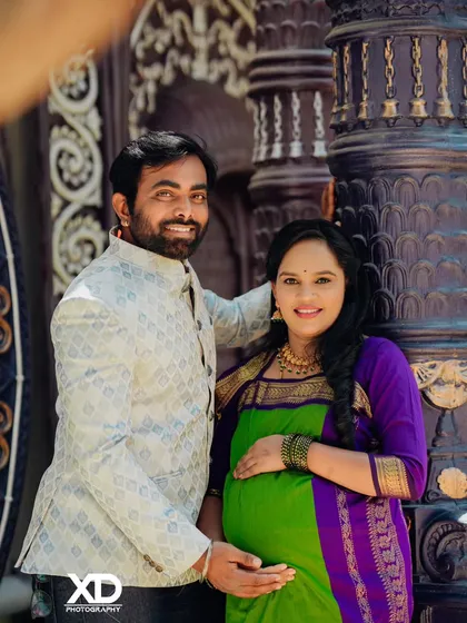 A cheerful couple portrait against a dark, ornate pillar, highlighting their bright smiles.