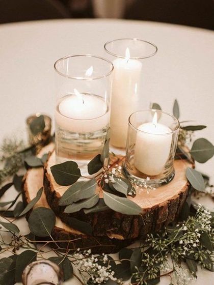 A rustic-chic centerpiece featuring candles on a wooden log slice, surrounded by eucalyptus and baby's breath. This is perfect for a farmhouse or bohemian-themed wedding.