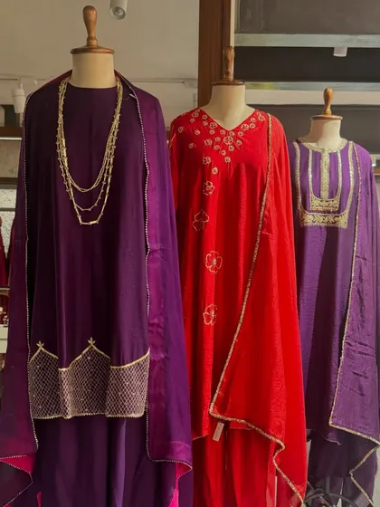 A royal display of purple and red. These outfits, with their gold embroidery and sheer dupattas, are curated for grand celebrations.