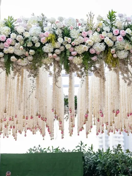 A detail shot of the intricate floral work, featuring thousands of tuberose strings and fresh roses that create a delicate, fragrant curtain effect under the main canopy.