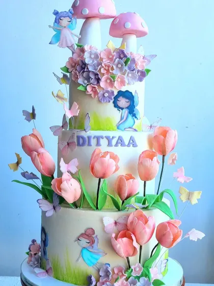 A close-up of the enchanted forest cake, showing the hand-painted details, sugar tulips, and tiny fairies.
