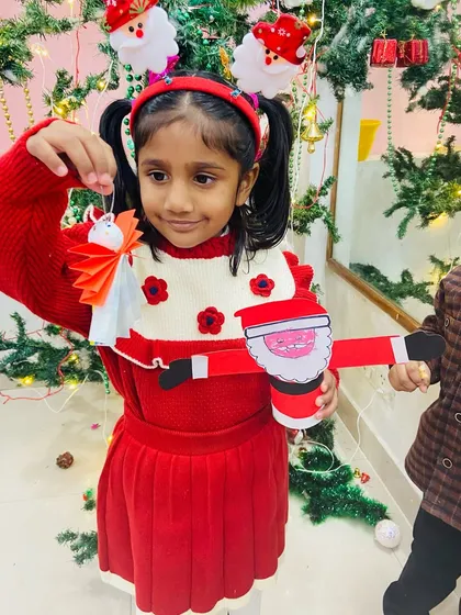 This student shows off her complete set of Christmas crafts, including a paper angel and a Santa holder.