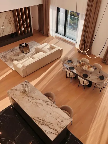 An overhead view of a luxurious open-plan space, where a simple Leda fixture provides elegant light over the dining area without obstructing the view.