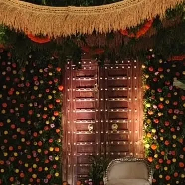 A close-up of a traditional wooden door used as a backdrop element, surrounded by a wall of marigold flowers, adding rustic charm and texture.