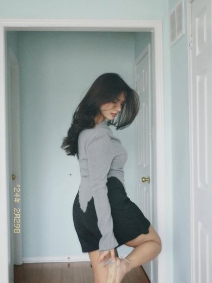 This indoor shot has a dreamy, film-like quality. It showcases a stylish grey asymmetrical top and black skirt, demonstrating how I can create an aesthetic mood even in a simple home setting.