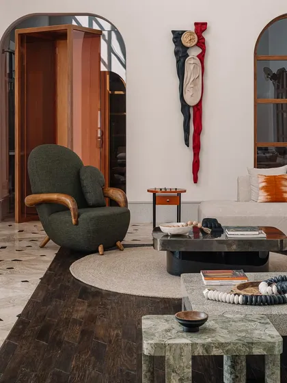 The 'Squal Man' wall sculpture, carved in ash wood with dramatic red and black stains, adds a powerful narrative element to this living room. It's a testament to our belief in collaborating with artists to create pieces with deep stories.