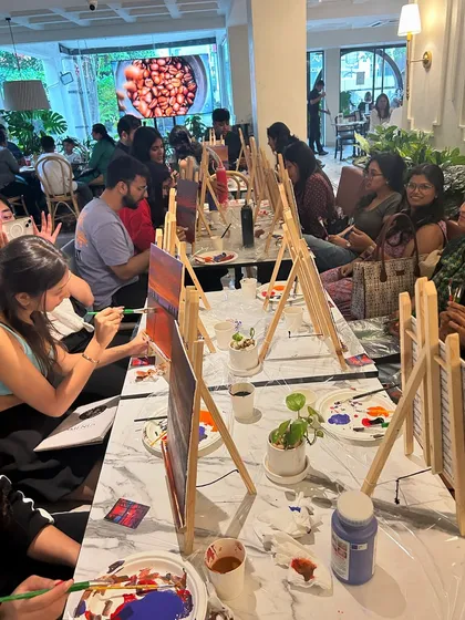 A wide shot of a packed workshop, capturing the lively and communal energy of a sip and paint event.