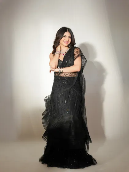 A full-length shot that embodies modern elegance. The nude, glossy makeup provides a perfect, subtle counterpoint to the dramatic black gown.