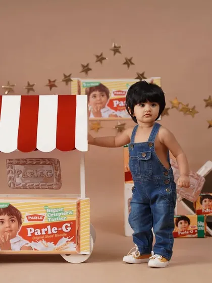 A full-length standing pose of the baby girl next to her Parle-G cart, perfect for a nostalgic and creative birthday memory.