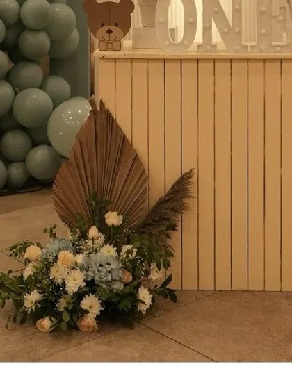 A modern floral arrangement used for a birthday party. We combined fresh hydrangeas and roses with dried pampas grass and a palm leaf for a contemporary, textured look.