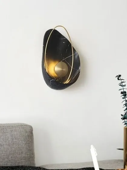 This sculptural wall lamp is crafted from black marble with delicate white veining, creating a piece that is as much art as it is a light source. The 'Bird Nest' design adds an organic, modern touch to this living space.