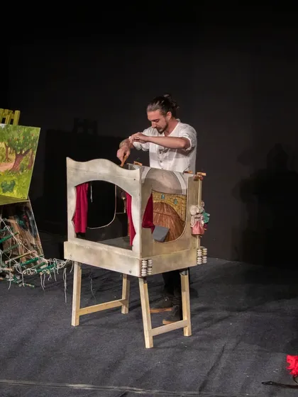 The puppeteer sets the stage for a scene in 'Dragon and the Devil', a show that uses multiple small stages and painted backdrops.