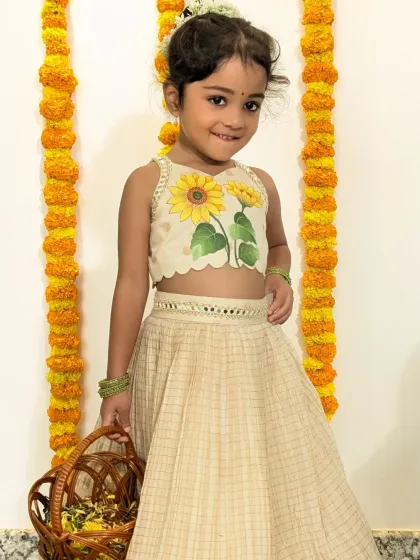 The sunflower lehenga set, radiating warmth and cheer. This full-length view shows the checked pattern of the skirt paired with the bright, hand-painted sunflower blouse, a beautiful choice for festivals like Onam or Diwali.