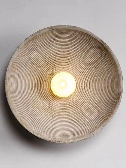 A simple, rustic wall sconce with a textured, bowl-like shape. This piece is perfect for adding a touch of wabi-sabi style.
