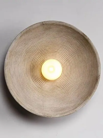 A simple, rustic wall sconce with a textured, bowl-like shape. This piece is perfect for adding a touch of wabi-sabi style.