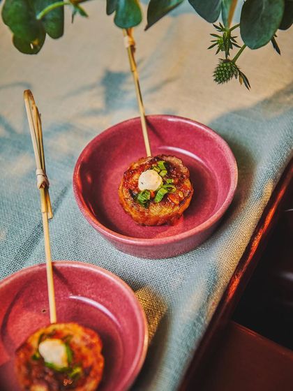 An artfully plated appetizer of our Chicken 65 Pinwheels with Smoked Raita. This dish is a perfect example of how we creatively re-imagine classic Indian flavors into modern, bite-sized delights.