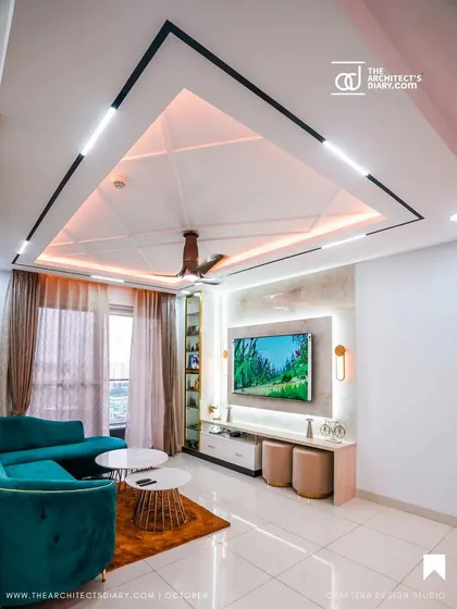 A modern living room designed for comfort and conversation. I focused on creating a sophisticated look with a striking false ceiling featuring geometric patterns and layered lighting, a plush teal sofa for a pop of color, and a sleek, minimalist TV unit. This space perfectly balances style and functionality.