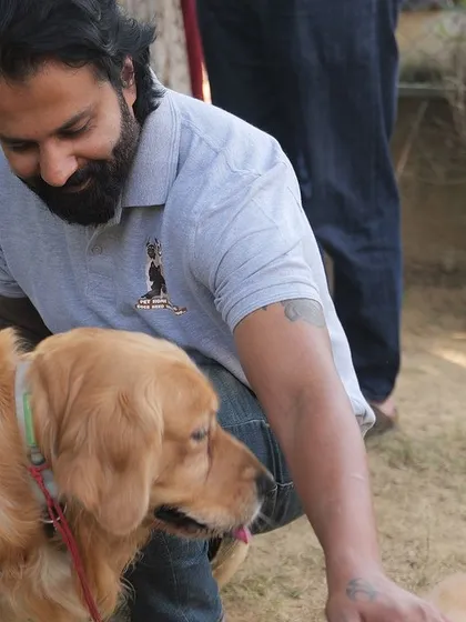 I'm seen here greeting a beautiful Golden Retriever wearing a service vest during our dog party. We welcome dogs of all backgrounds and roles, ensuring everyone feels comfortable and included.