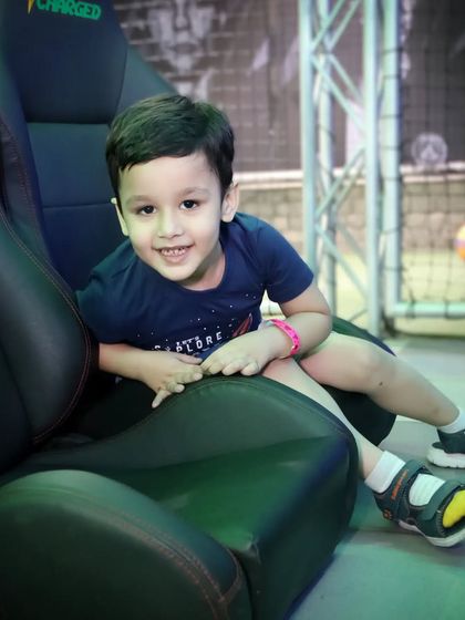 A young boy gives a happy, natural smile while sitting in a gaming chair. We aim for relaxed portraits that show genuine emotion.