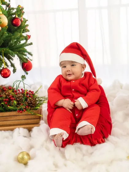 The cutest Santa in town, sitting happily by the Christmas tree. This festive sitter session is perfect for capturing your baby's joyful spirit during the holidays.