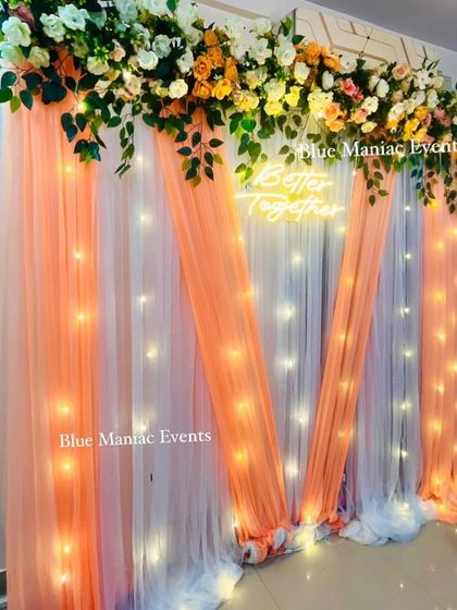 A beautiful 'Better Together' backdrop with peach and white drapes and a floral top border. This elegant design is perfect for anniversaries or intimate Roka ceremonies.