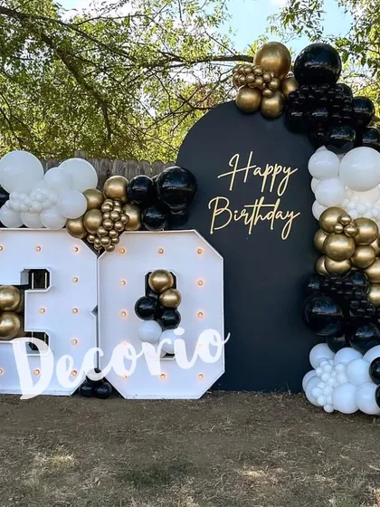 An outdoor 30th birthday party with a chic black, white, and gold theme. The setup features a circular backdrop and large marquee numbers, perfect for a stylish garden or backyard celebration.