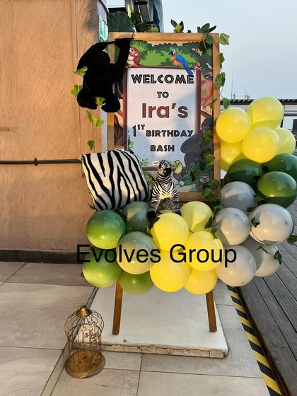 The jungle-themed welcome sign for Ira's first birthday bash. The decor includes themed props like a hanging monkey and a zebra to greet guests.