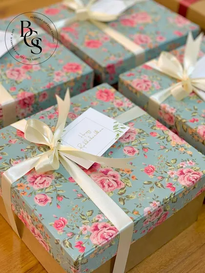 A collection of gift boxes featuring a beautiful vintage floral print paper. The soft blue background and pink roses are complemented by a simple cream ribbon, creating a romantic and timeless look.