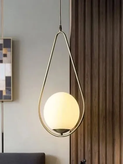 A remarkable pendant light featuring a glowing white globe held within a brass, teardrop-shaped frame. The imported gold finish gives it a luxurious feel, perfect for adding a touch of elegance to a modern room.