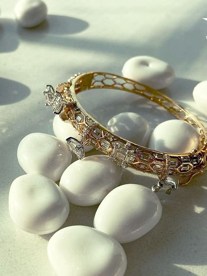 This captivating bracelet with its honeycomb gold pattern and diamond charms encircles your wrist, adding a subtle elegance to any outfit.