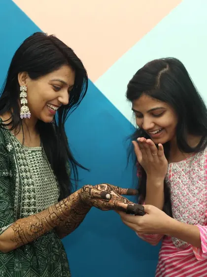 A candid moment of laughter and admiration as the bride shows her freshly applied mehandi to a friend. We capture the genuine reactions and joy surrounding the pre-wedding rituals.