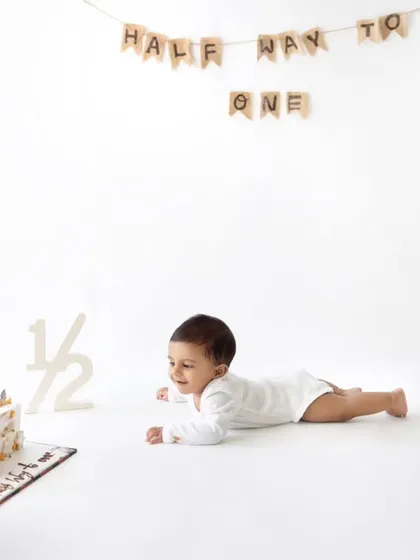 A minimalist and modern half-birthday shoot, with the baby crawling towards a "Half Way To One" cake.